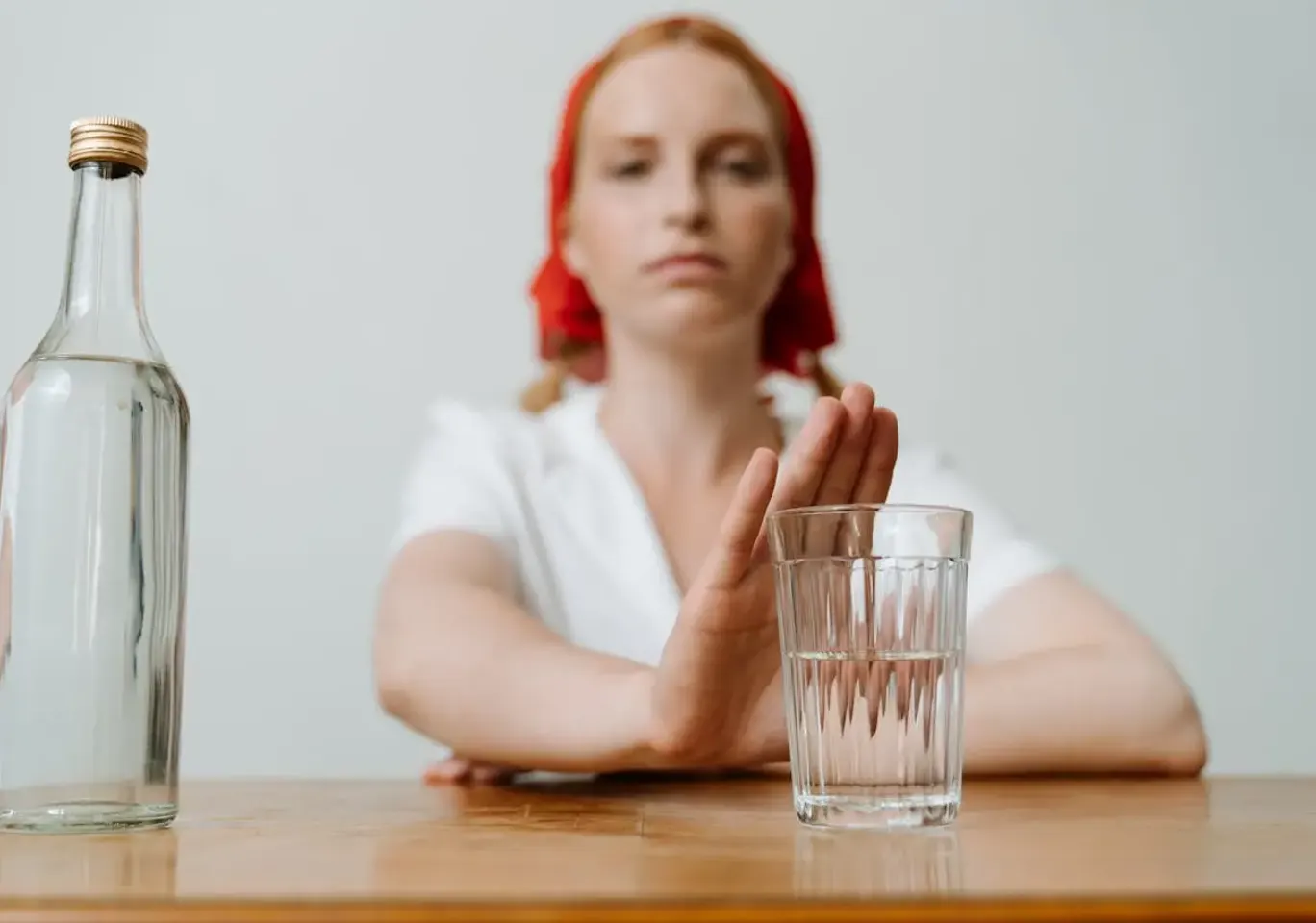 Leczenie alkoholizmu Olsztyn: kobieta odsuwa butelkę i sięga po wodę